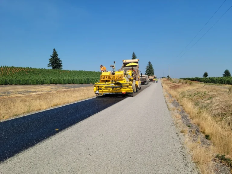 Asphalt paving crew laying fresh asphalt on a rural road