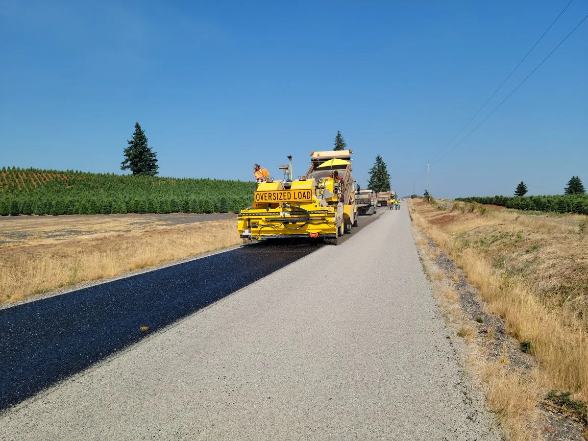 Asphalt paving crew laying fresh asphalt on a rural road