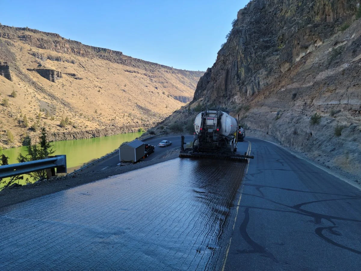 Asphalt distributor truck spraying tack coat on a mountain highway